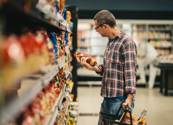 Imagem colorida, um homem avaliando um produto dentro de um mercado - Metrópoles