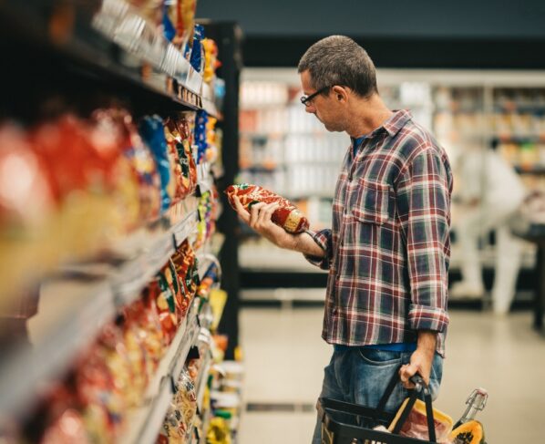Imagem colorida, um homem avaliando um produto dentro de um mercado - Metrópoles